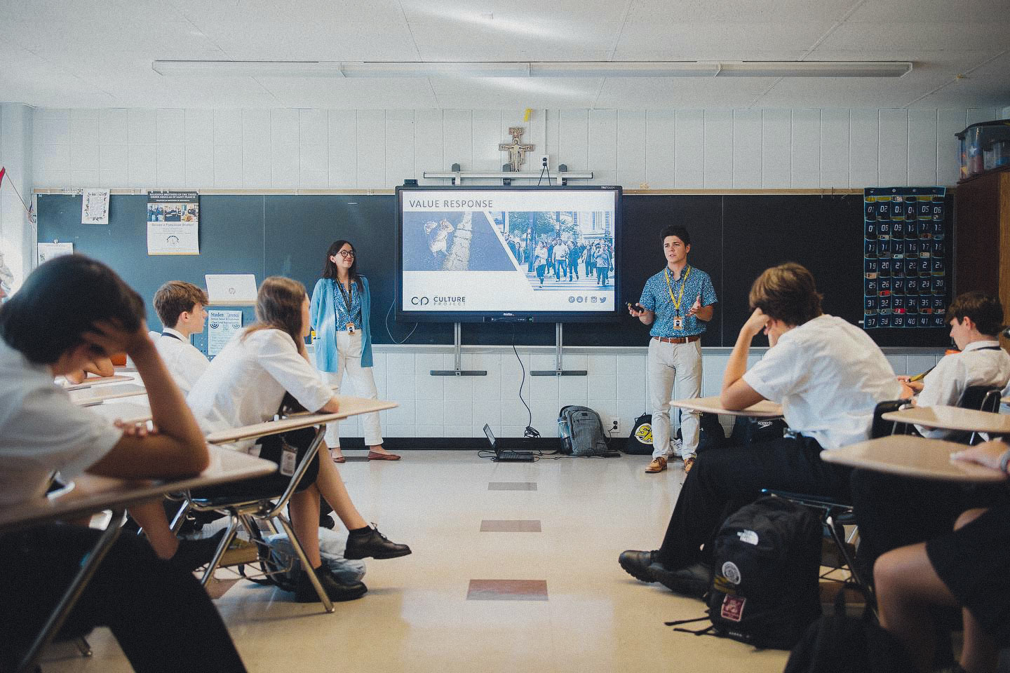 Two Culture Project missionaries present to a group of highschoolers in a school room